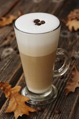 Coffee latte with beans and oak leaves on the table