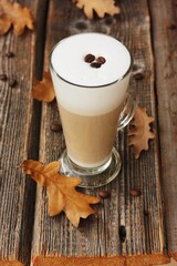 Coffee latte with beans and oak leaves on the table