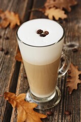 Coffee latte with beans and oak leaves on the table