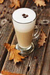 Coffee latte with beans and oak leaves on the table