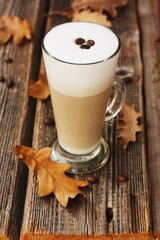 Coffee latte with beans and oak leaves on the table