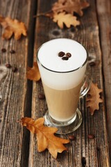 Coffee latte with beans and oak leaves on the table