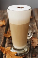 Coffee latte with beans and oak leaves on the table
