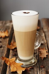 Coffee latte with beans and oak leaves on the table