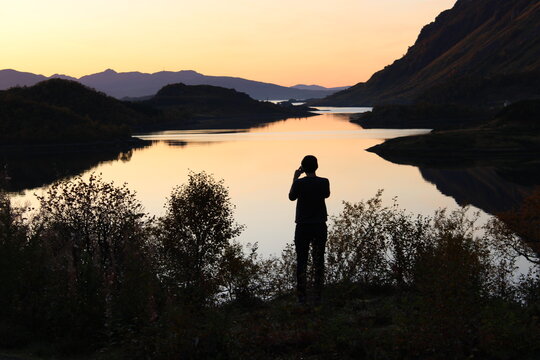 Sunset on Lofoten islands with the silhouette of a man taking pictures 