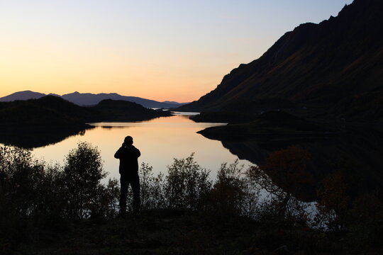 Sunset on Lofoten islands with the silhouette of a man taking pictures 