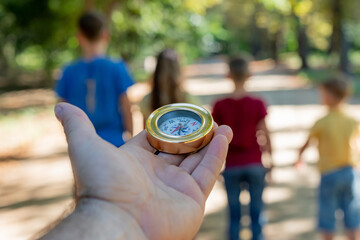 Naklejka premium Compass in hand against the background of standing children in the forest.