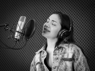 Monochrome or black and white image, pretty Asian woman singing in voice record studio....