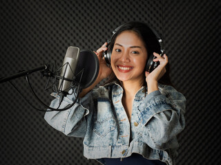 Pretty Asian woman singing in the voice record studio.  Professional musician or singer recording music in modern sound studio