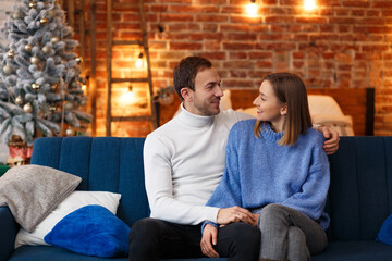 Portrait of beautiful smiling couple hugging at Christmas eve. Beautiful young couple at home enjoying spending time together. Winter holidays, Christmas celebrations, New Year concept.