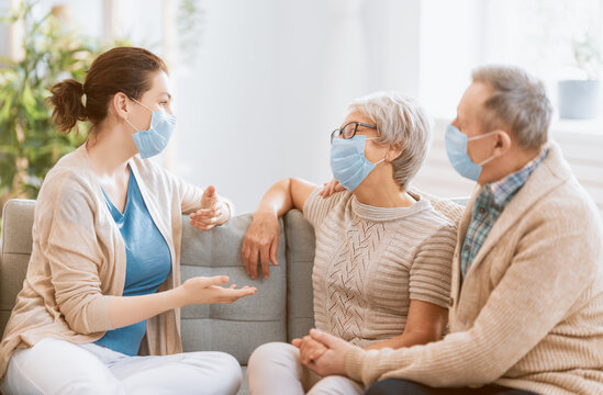 Adult Daughter And Senior Parents Wearing Facemasks