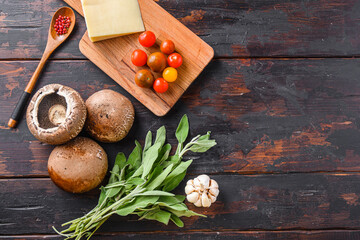 Portabello mushrooms ingredients for baking, cheddar cheese, cherry tomatoes and sage  on old dark wood background, top view s[ace for text.