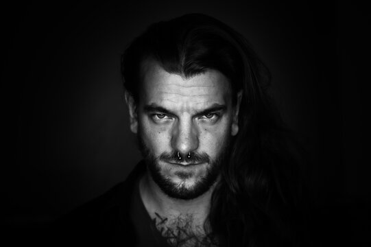 Man with long hair looks seriously and determined at the camera on an black and white image