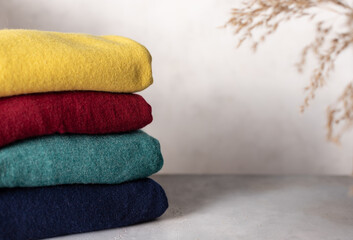 stack of different jumpers on a gray background. Cozy woolen clothes. place for text. close-up