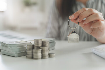 Property investment, Hands holding key house with coins and banknote.