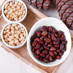 Shelled and unshelled pine nuts and pine cones on the white table