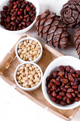 Shelled and unshelled pine nuts and pine cones on the white table