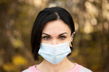 Beautiful caucasian woman with disposable face mask. Protection versus viruses and infection. COVID-19 pandemic coronavirus.
