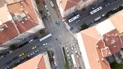 Aerial view of the city traffics at the center. Vehicles are moving on the road between buildings.
