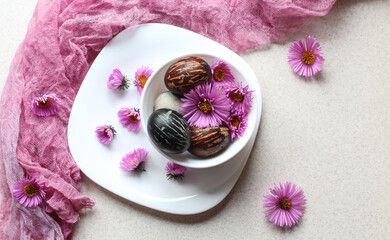 Dark-colored Easter eggs on a white dish with a purple napkin, close-up, top view