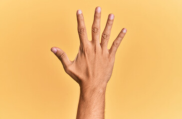 Arm and hand of caucasian man over yellow isolated background counting number 5 showing five fingers