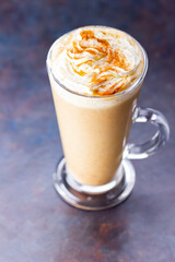Pumpkin latte on a dark background. Pumpkin spice latte with whipped cream. Autumn drink. Minimalism. Copy space