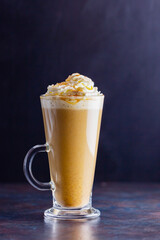 Pumpkin latte on a dark background. Pumpkin spice latte with whipped cream. Autumn drink. Minimalism. Copy space
