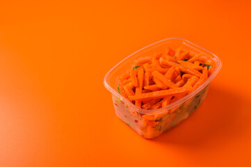 Frozen vegetables carrot in a plastic tray on an orange background, selective focus, concept diets and healthy eating with copy space close up