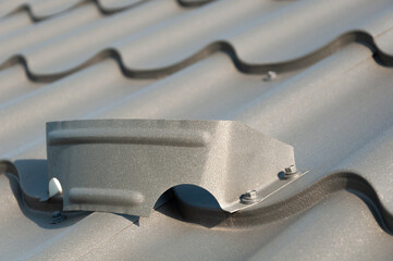 Gray metal roof tiles and snow guards. House roofing system close-up.