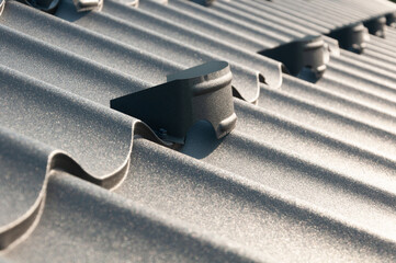Gray metal roof tiles and snow guards. House roofing system close-up.
