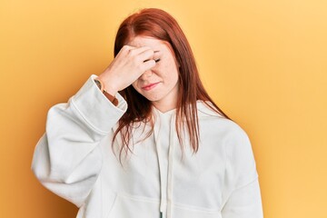 Young red head girl wearing casual sweatshirt tired rubbing nose and eyes feeling fatigue and headache. stress and frustration concept.