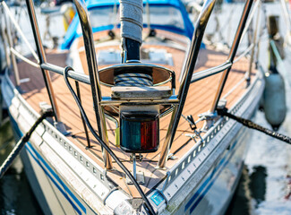 Close up of the bow of a sail boat moored in a marina, with lines, ropes and navigational lantern...