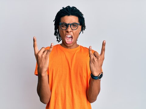 Young african american man wearing casual clothes and glasses shouting with crazy expression doing rock symbol with hands up. music star. heavy concept.