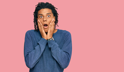 Young african american man wearing casual winter sweater afraid and shocked, surprise and amazed...
