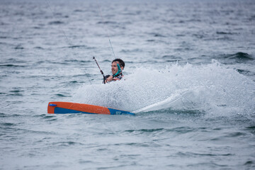 A man creates a big wave of water as he kite surfs in the ocean