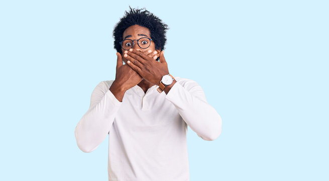 Handsome african american man with afro hair wearing casual clothes and glasses shocked covering mouth with hands for mistake. secret concept.