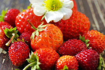 Several fresh ripe red strawberries on a wooden table. Macro photography. Focus on the berry in the center.