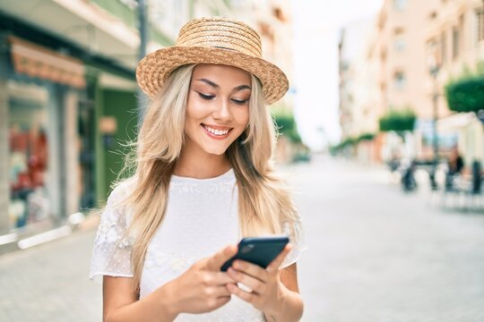 Young caucasian tourist girl smiling happy using smartphone at street of city.