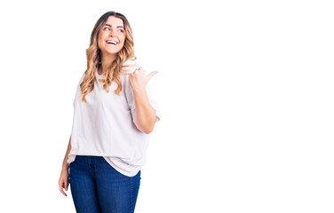 Young caucasian woman wearing casual clothes smiling with happy face looking and pointing to the side with thumb up.