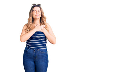 Young caucasian woman wearing casual clothes and sunglasses smiling with hands on chest with closed eyes and grateful gesture on face. health concept.