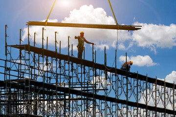 Man working on construction site with scaffold and building with sky background,scaffolding for...