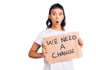 Young woman holding we need a change banner scared and amazed with open mouth for surprise, disbelief face