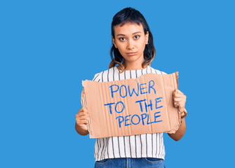 Young woman holding power to the people banner thinking attitude and sober expression looking self confident