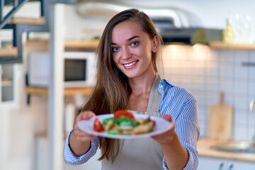 Portrait of a beautiful happy cute joyful smiling cooking woman with a plate of fresh salad