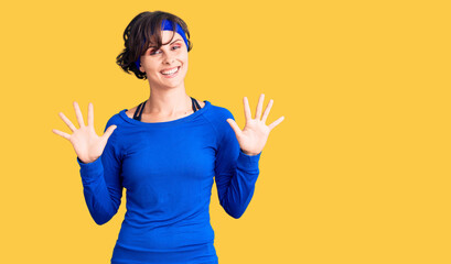 Beautiful young woman with short hair wearing training workout clothes showing and pointing up with fingers number ten while smiling confident and happy.
