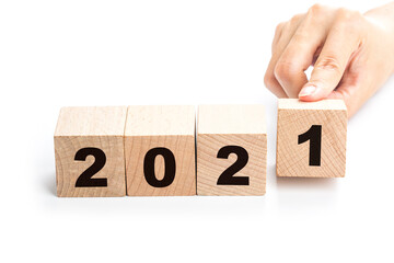 Hand flips a block changing 2020 to 2021. New year beginning. Holidays and Christmas.