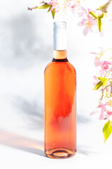 Rose wine bottle on the white table and pink flowers. Rosado, rosato or blush wine tasting in wineshop, bar concept. Copy Space