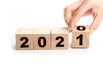 Hand flips a block changing 2020 to 2021. New year beginning. Holidays and Christmas.