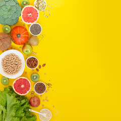 Superfoods on yellow background with copy space. Vegetables, fruits, herbs and seeds