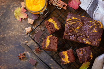Baking Thanksgiving Day. Homemade chocolate brownie cake dessert with pumpkin puree and spices on a rustic wooden background. Top view flat lay background. Copy space.